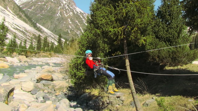 a man crossing the mountain river by a rope crossing
