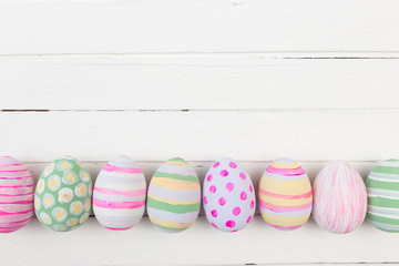 Easter eggs painted in pastel colors on a white wood background