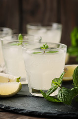 Fresh cocktail with lemon, ice and mint on the vintage table