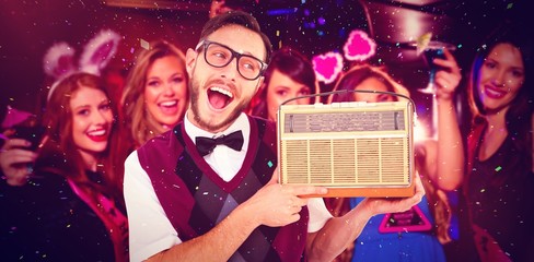 Composite image of geeky hipster holding a retro radio
