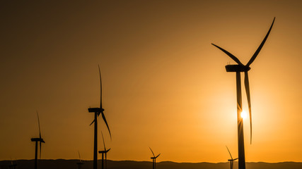 Siluetas de aerogeneradores en una puesta de sol