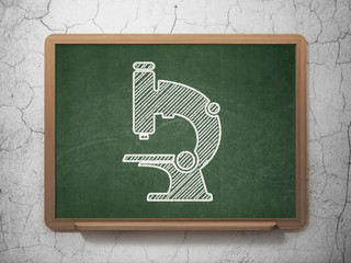 Science concept: Microscope on chalkboard background