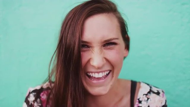 Close up of a beautiful girl laughing and taking pictures with her cell phone, slow motion