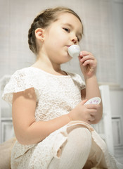 Expressive beautiful little girl having a tea party. Children's play.