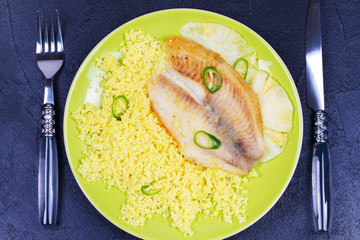 Pan sauteed fish on pineapple planks with couscous. View from above, top studio shot