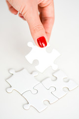 Woman hand fitting the right piece of puzzle suggesting business networking concept