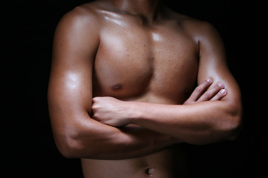 A hunky young asian male folding his hands with muscular chest