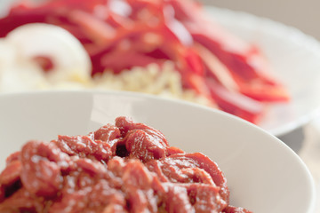 Beef steak finely sliced into track - shaped cutlets, marinated prior cooking or frying; close up, selective focus