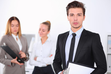 Fototapeta premium Cheerful business man in office with colleagues in the background, sturt up team