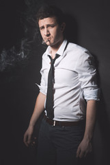 Young smoker with rolled up sleeves looking at camera