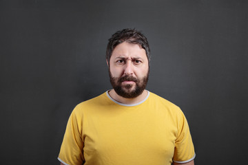 Fototapeta premium Frowning man looking at the camera. On dark chalkboard