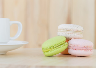 Sweet Macaroons with cup on wooden background.