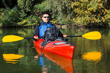 The man is kayaking on the river.