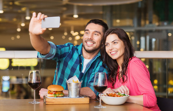 couple taking selfie by smartphone at restaurant