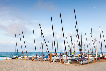Sailing boats lay in a row on the sandy beach
