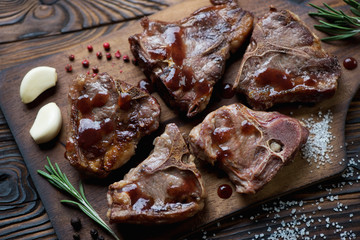 Closeup of grilled lamb T-bone steaks with sauce, studio shot
