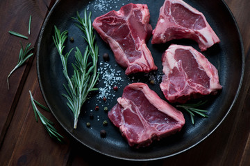 Close-up of raw T-bone lamb steaks in a frying pan, top view