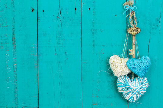 Skeleton key and three rope hearts hanging on teal blue door