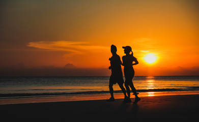 Fototapeta premium Young couple: man and woman run together on a sunset on lake coa