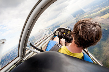 pilot in the cockpit of the plane, glider gliding in the air over cities and countryside - 97665167