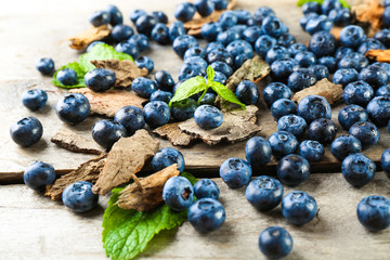 Tasty ripe blueberries with green leaves on wooden table close up