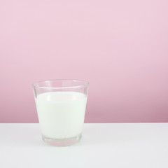The glass of fresh milk on the white table.