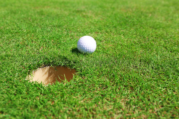Golf ball on lip of cup on the green golf course