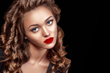 Fototapeta premium Beautiful Woman Model with Curls, Red Matte lips. Beauty face closeup. Isolated on Black Background. Long Shiny Curly Hair. Hairstyle..