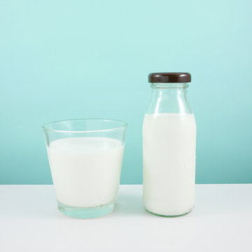 The glass and bottle of fresh milk on the white table.