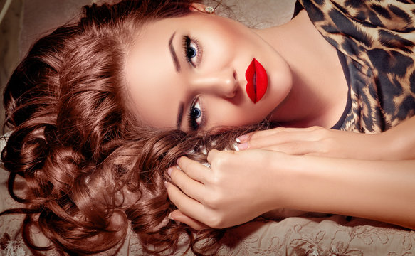 Fashion Model Girl Face Portrait with Hands touching Curly Hair, Beauty Woman Make up, Long Lashes, Blue Eyes, Red Sexy Lips, Makeup Closeup, Perfect skin, Holiday Luxury make-up.