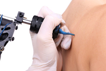 Tattooist draws on the woman's right shoulder-blade on white background, close up