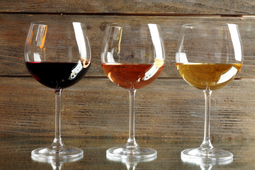 Glasses with white, rose and red wine on wooden background