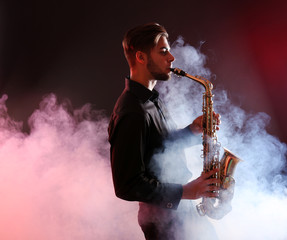Naklejka na ściany i meble Young man professionally plays sax in red smoke