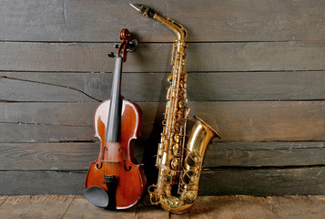 Beautiful golden saxophone with violin on wooden background