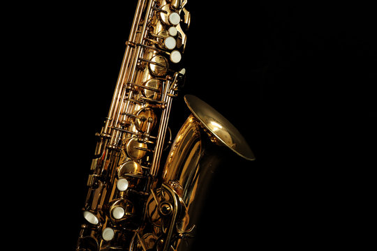 Beautiful golden saxophone on black background, close up