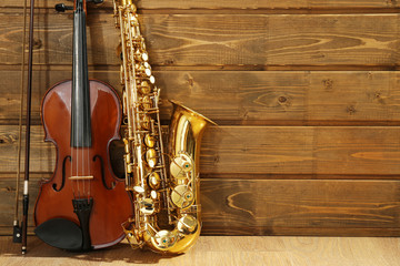 Violin and saxophone on wooden background