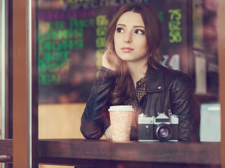 Young woman drinking coffee sitting indoor in urban cafe. Cafe city lifestyle. Casual portrait of teenager girl. Toned