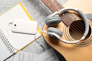 Classical guitar and headphones with phone on grey background