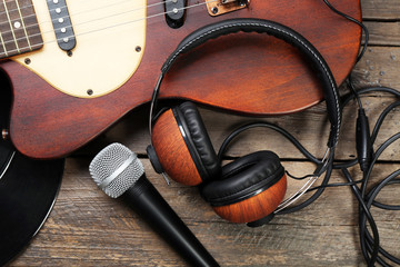 Electric guitar and headphones with microphone on wooden background