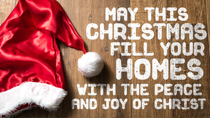 May this Christmas Fill Your Homes With the Peace and Joy of Christ written on wooden with Santa Hat