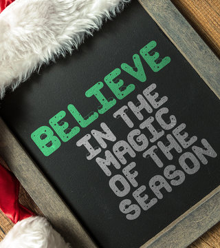 Believe in the Magic of the Season written on blackboard with santa hat
