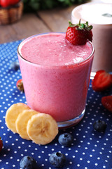 Glasses of fresh cold smoothie with fruit and berries, on blue tablecloth background