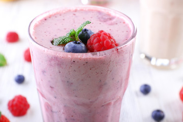 Milkshakes with berries on light wooden background, close-up