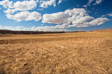 White clouds floating over dry grass land of plateau