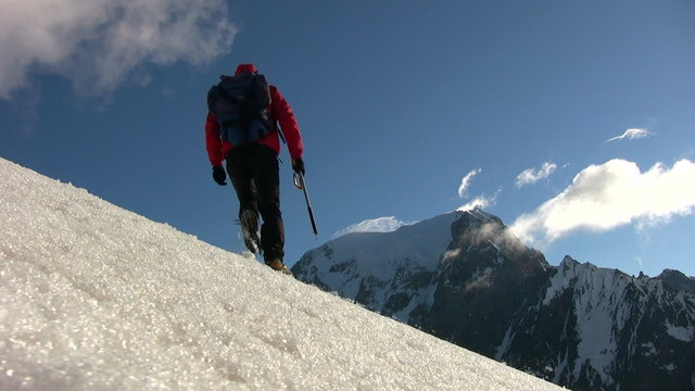Mountain climber walks on a glacier; in background the beautiful view on Mont Blanc, Courmayer, Italy.
