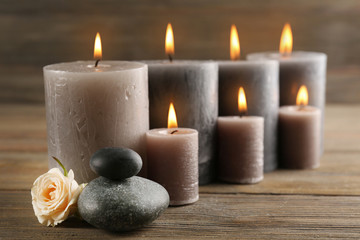 Fototapeta na wymiar Alight wax grey candles with roses on wooden background