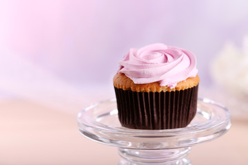 Tasty cupcake on stand, on light background