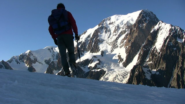 Mountain climber walks on a glacier; in background the beautiful view on Mont Blanc, italian Alps, Europe.