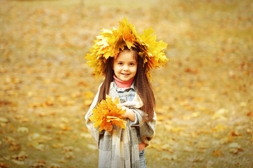 Happy young girl in yellow autumn wreath  in park