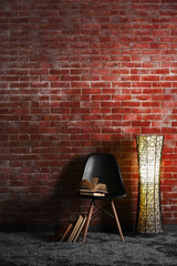 Black modern chair with lamp and books on brick wall background